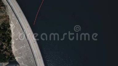 无人驾驶飞机在一条河前的大坝上的一条路上和一辆<strong>路过</strong>的红色<strong>汽车</strong>上射击